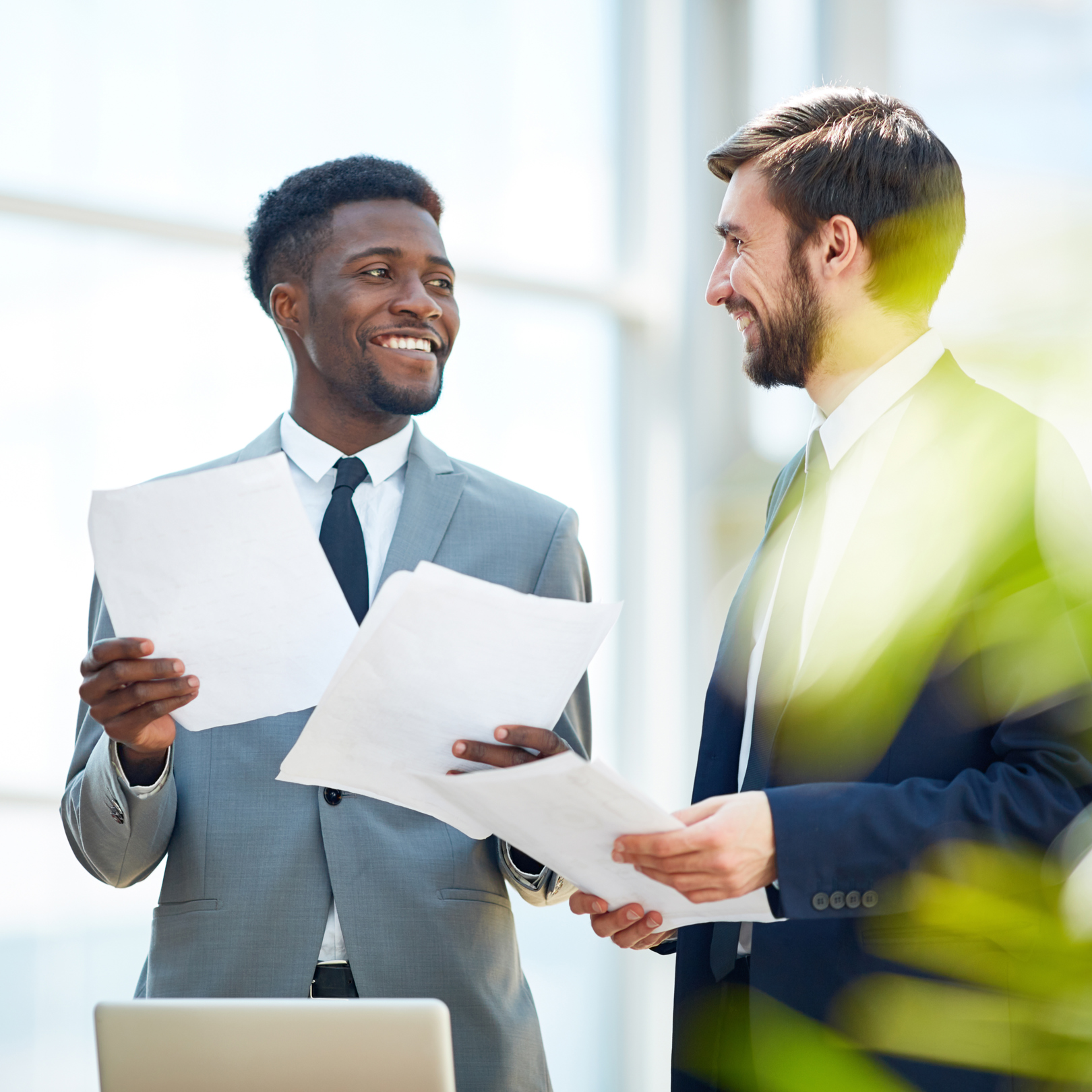 Photo de deux hommes en costume souriant et tenant des documents