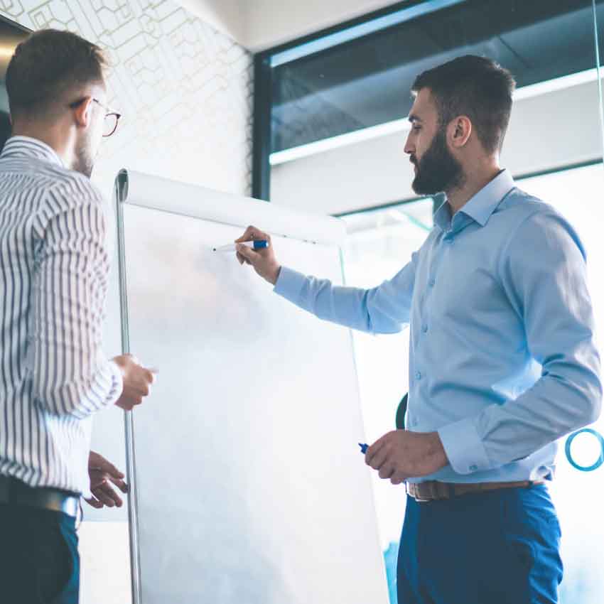 deux hommes travaillant sur un tableau blanc